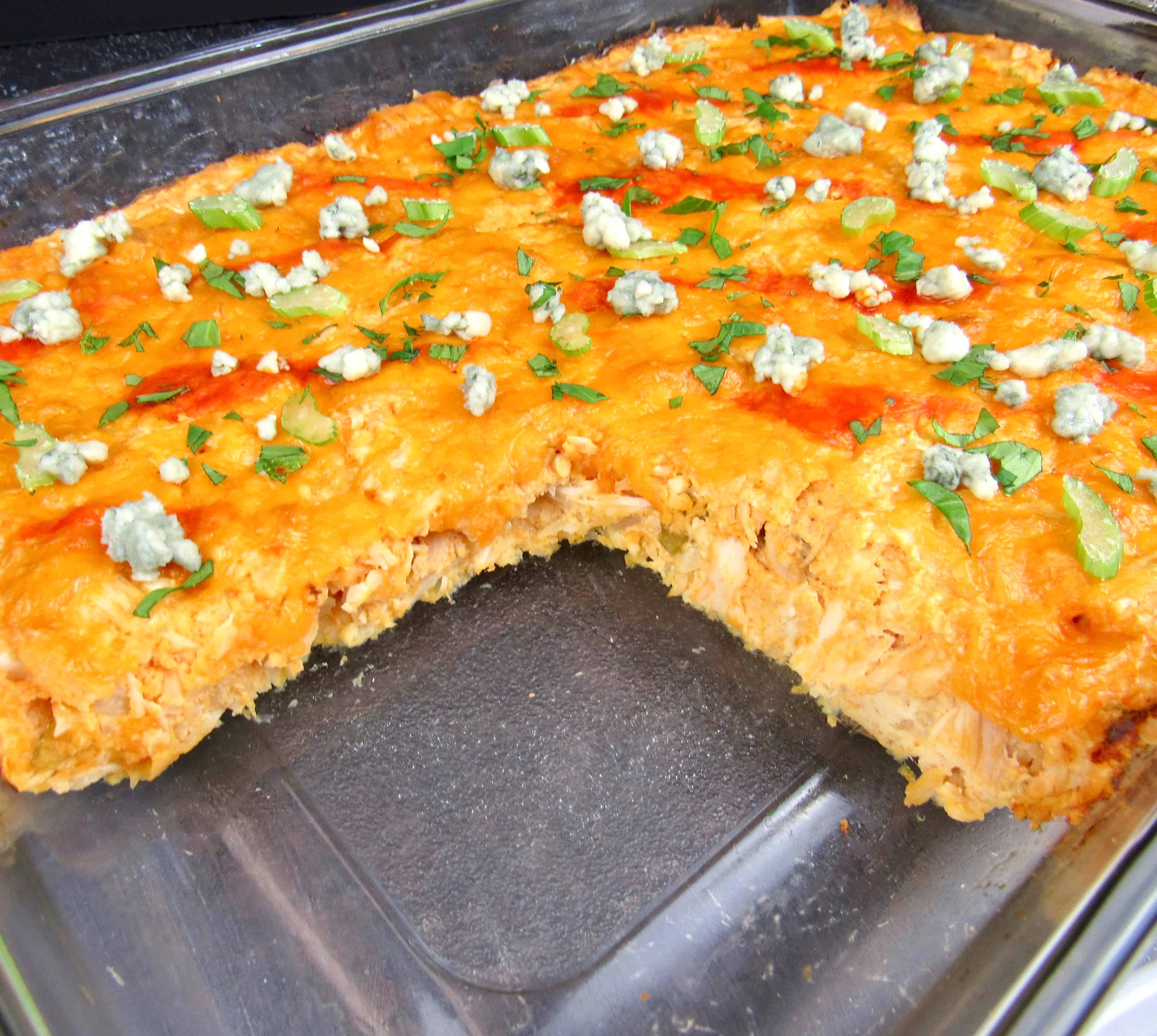 buffalo chicken casserole in glass baking dish with slice missing