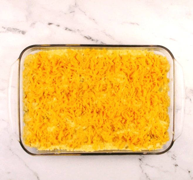 buffalo chicken casserole with cheese on top unbaked in glass dish