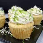 closeup of frosted coconut cupcakes with lime zest and coconut flakes