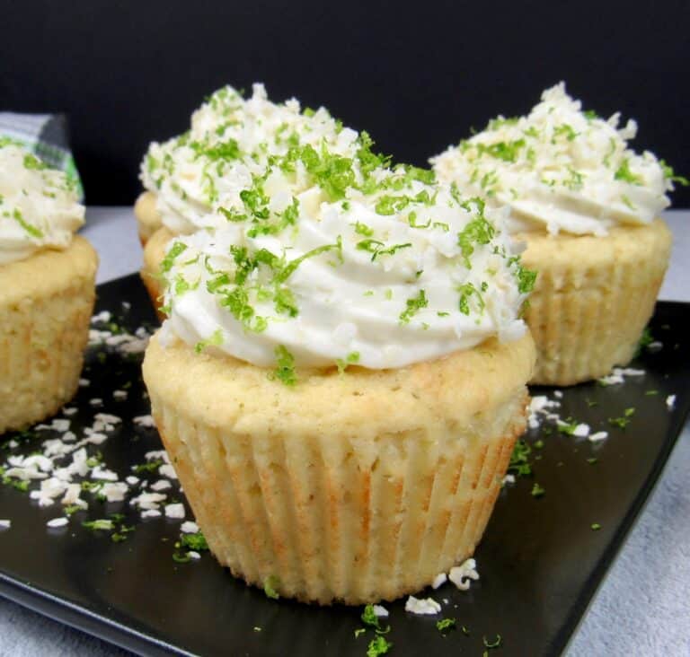 closeup of frosted coconut cupcakes with lime zest and coconut flakes