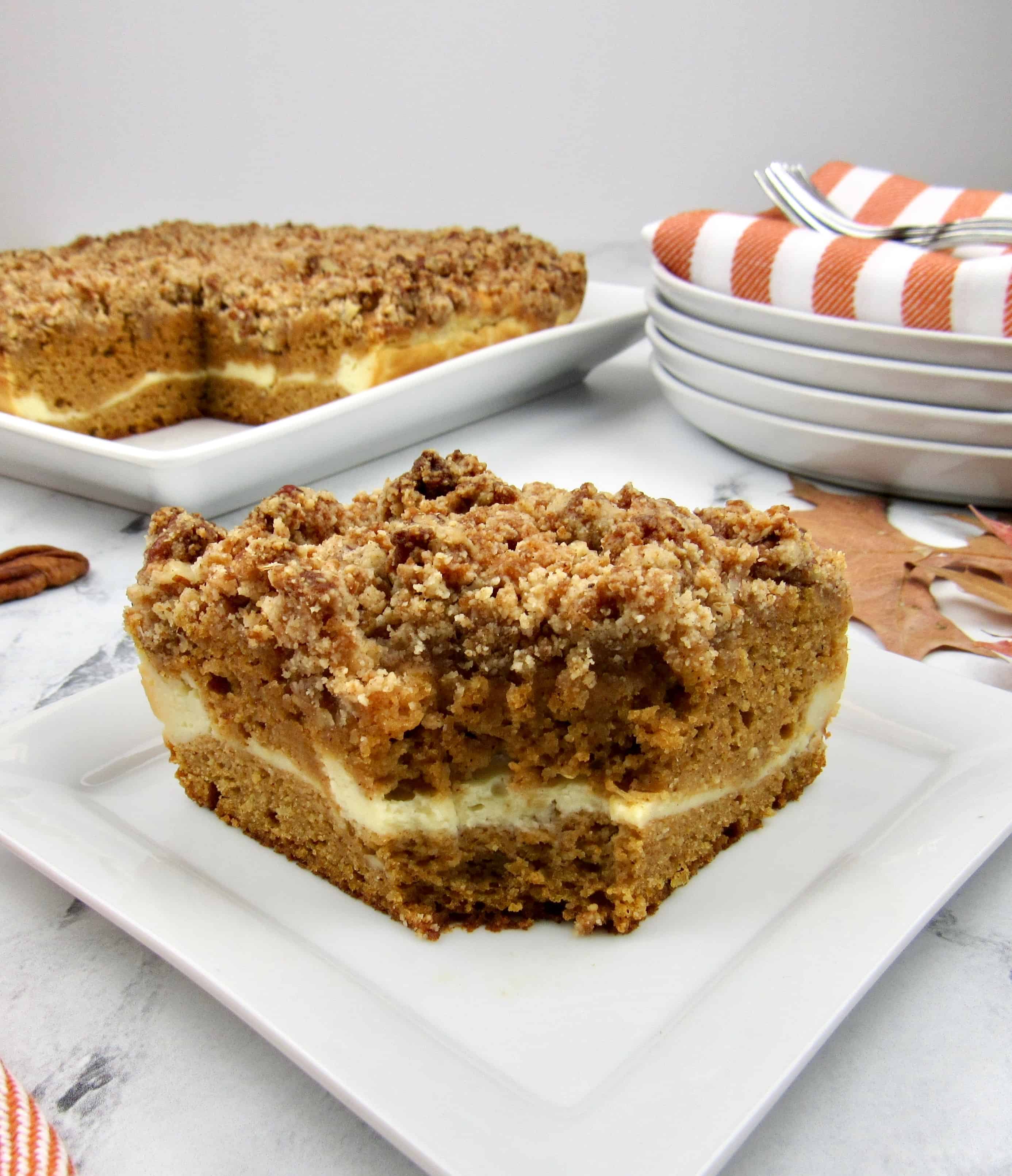 closeup of pumpkin coffee cake with bites take out coffee cake in the background