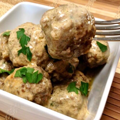 Swedish Meatballs in white bowl with a fork holding up one