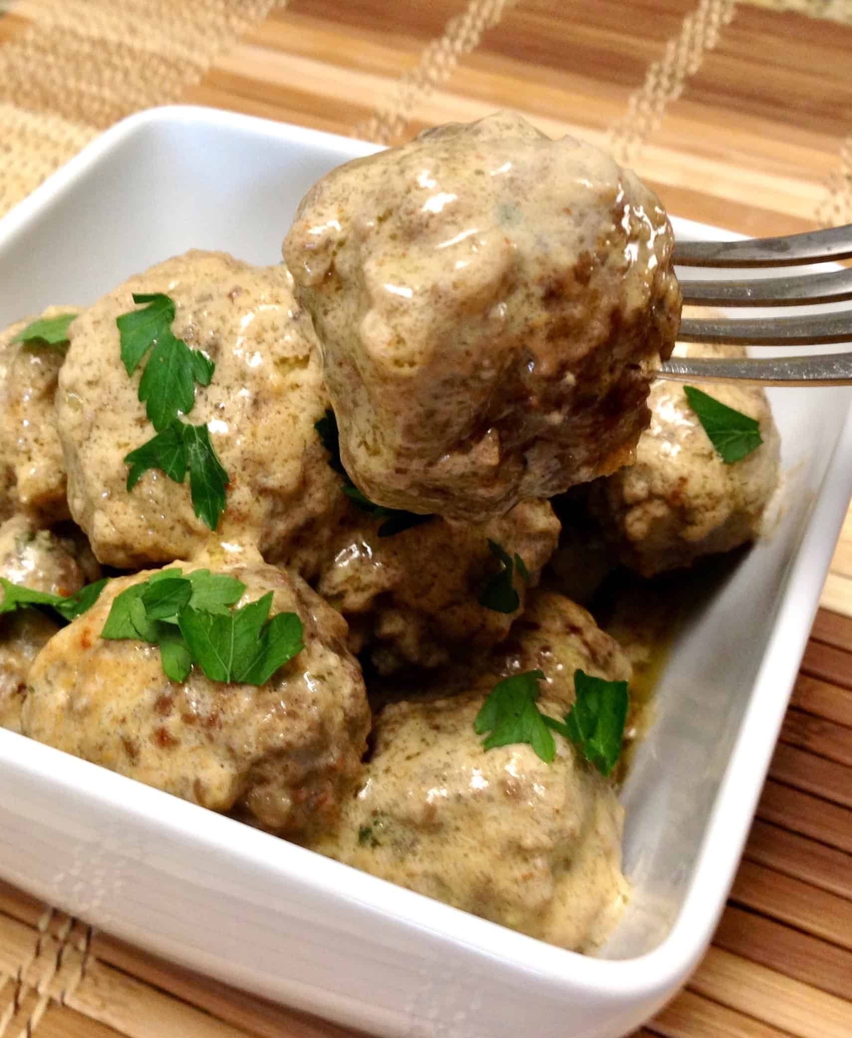 Swedish Meatballs in white bowl with a fork holding up one