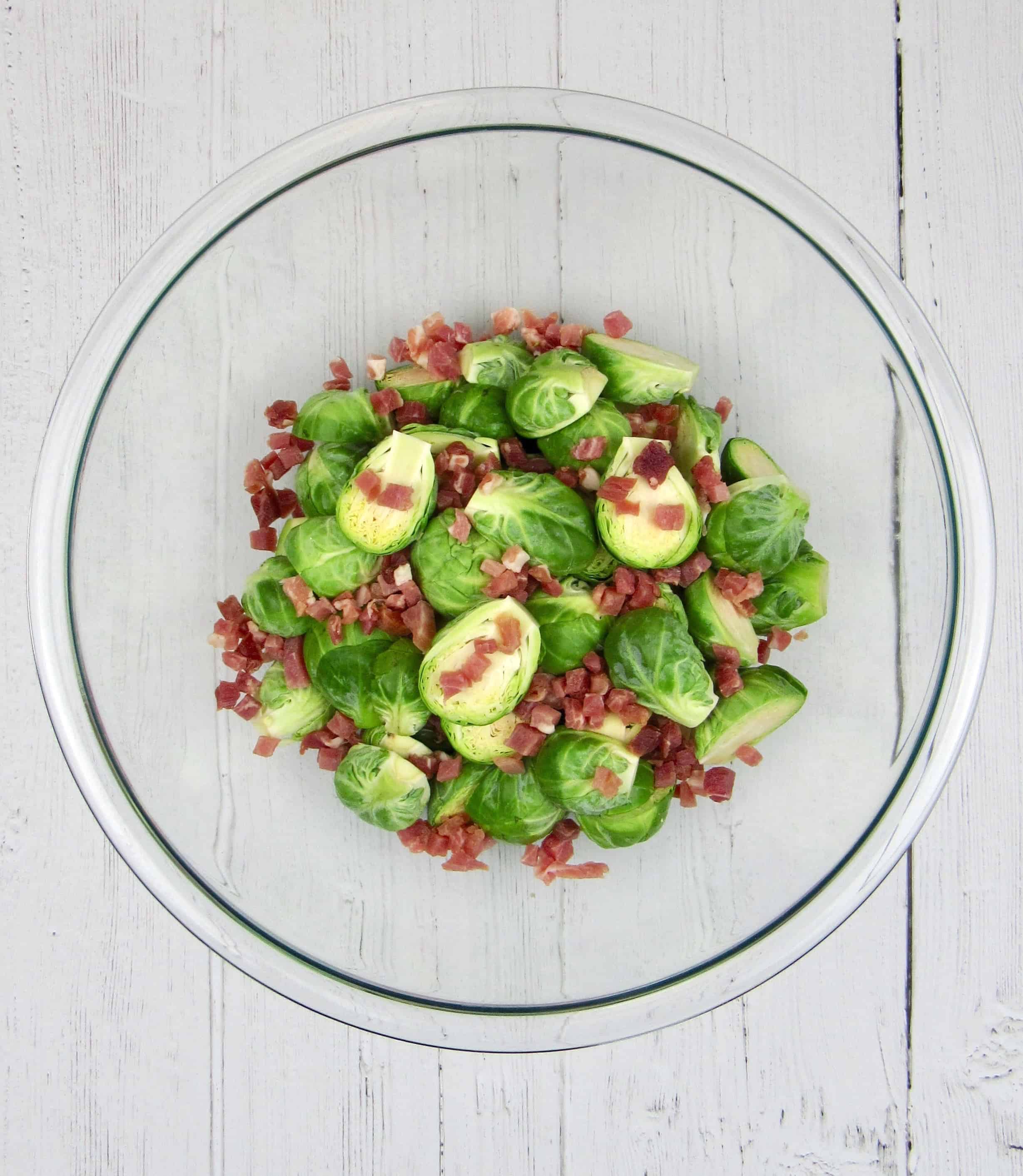 brussels sprouts cut up in glass bowl with pancetta