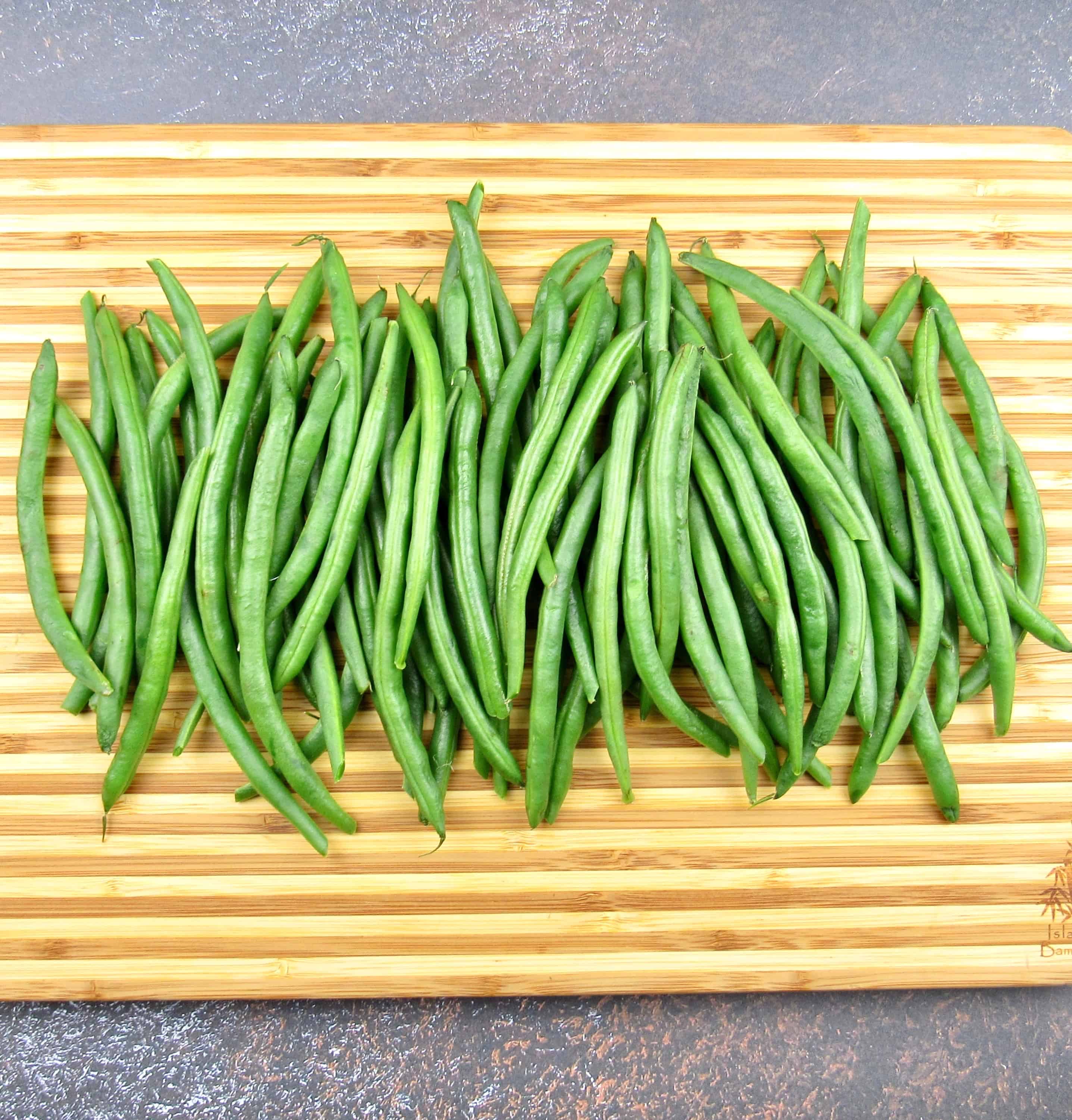 raw green beans lined up on cutting board