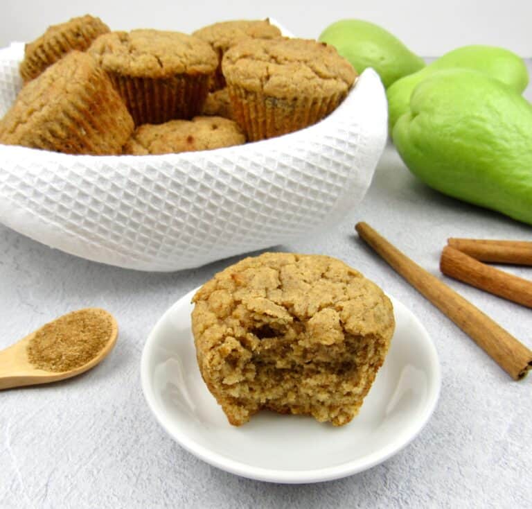 keto mock apple muffin with bite taken out and basket with muffins in the background