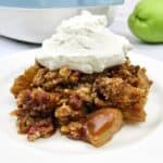 closeup of mock apple crumble on white plate with whip cream on top