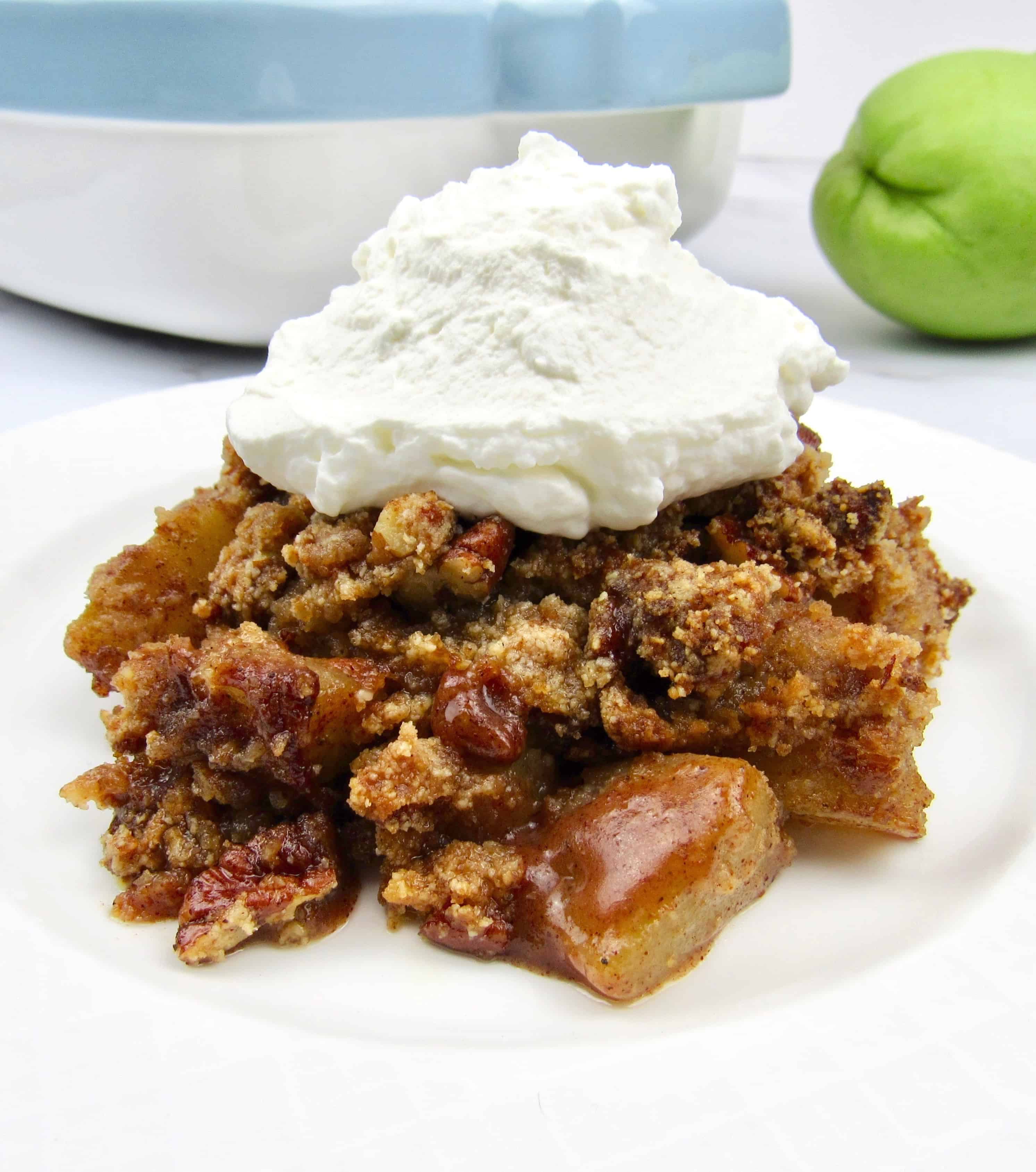 closeup of mock apple crumble on white plate with whip cream on top