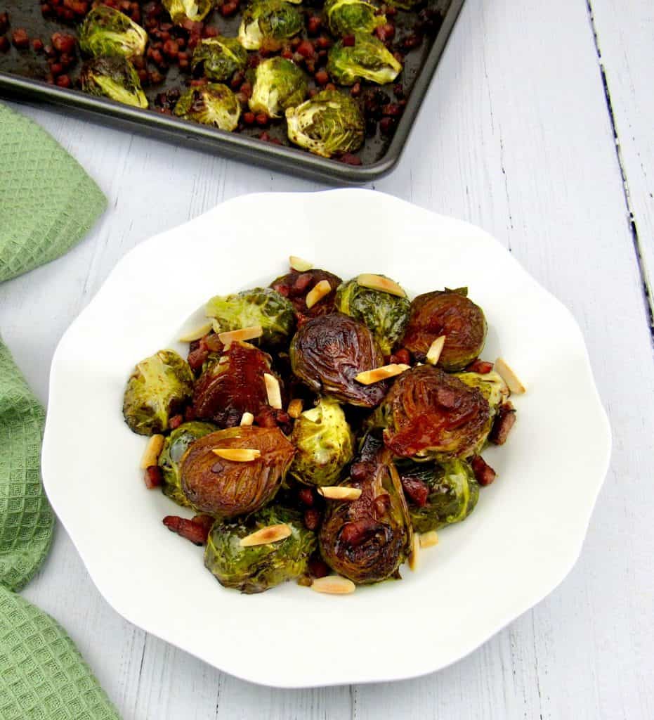 overhead view of brussels sprouts in white dish with sheet pan in background