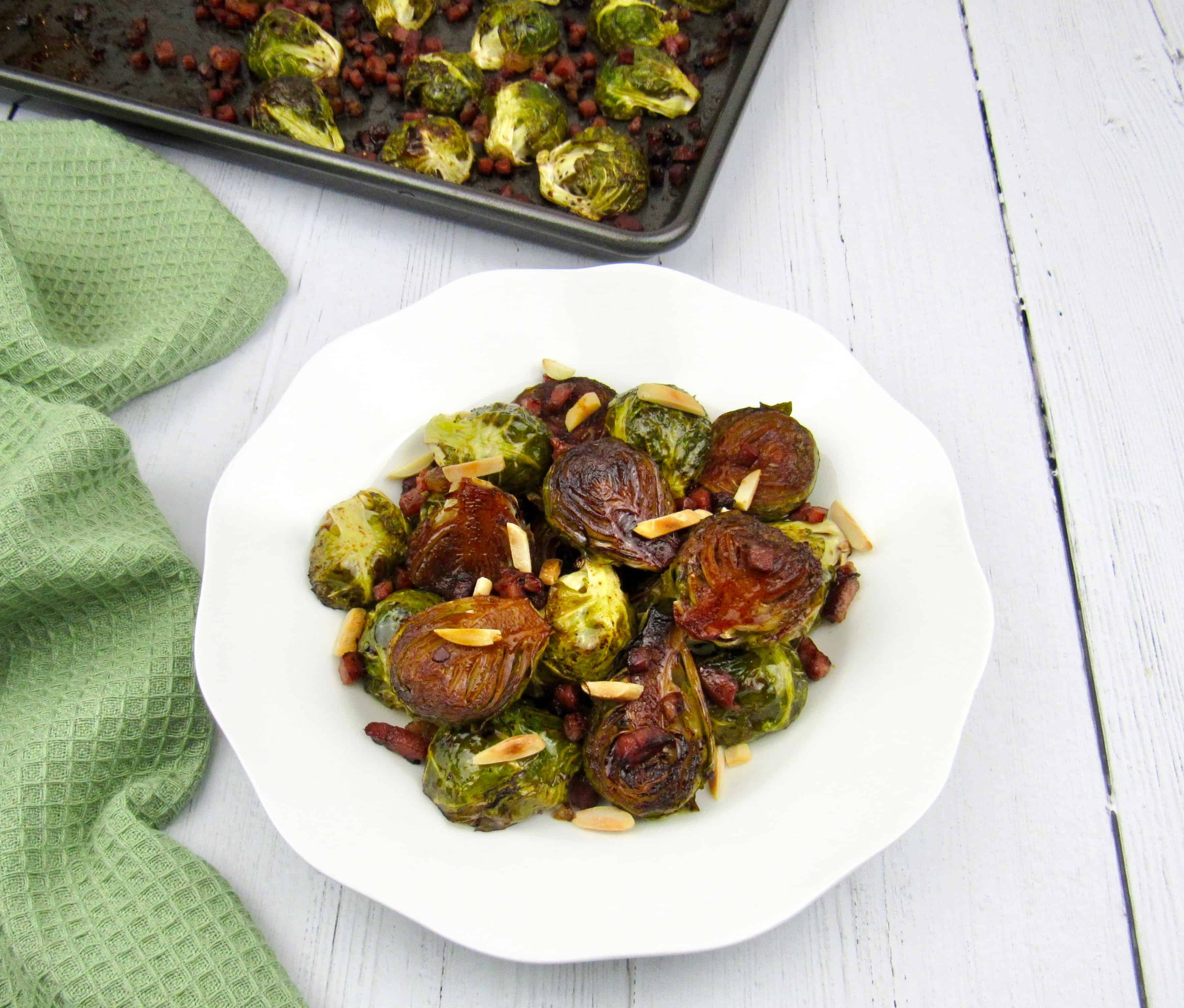 overhead view of brussels sprouts in white dish with sheet pan in background