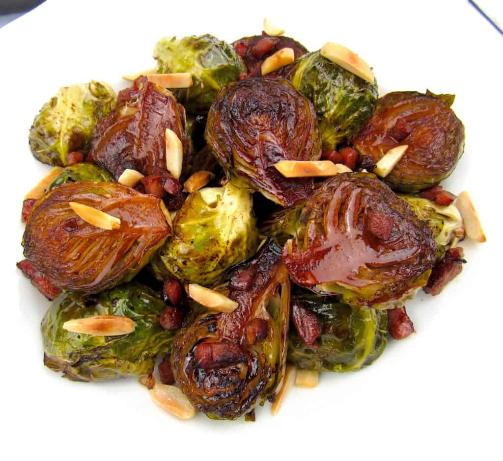 overhead view of brussels sprouts in white dish with sheet pan in background