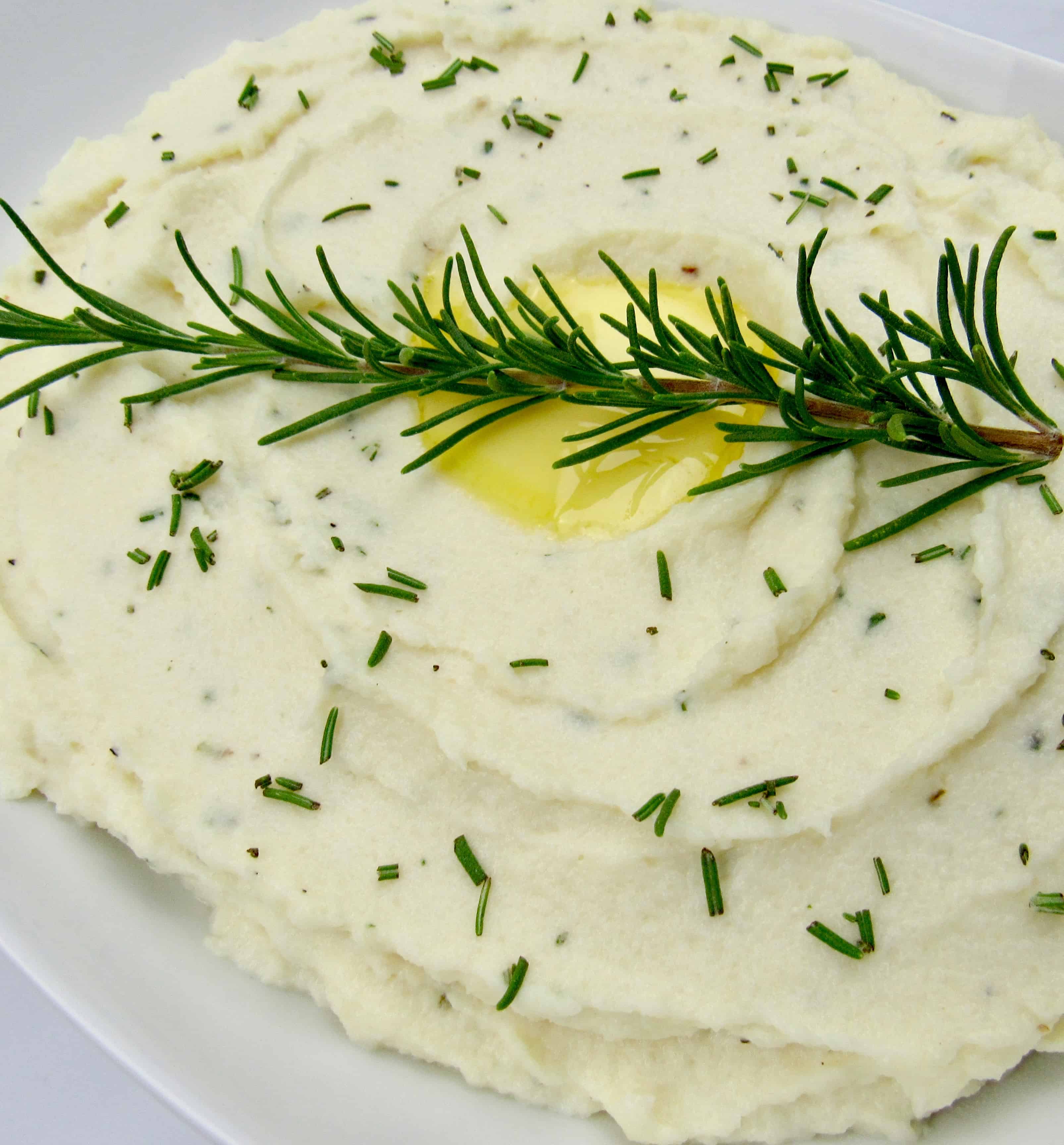 mashed cauliflower closeup with rosemary sprig on top