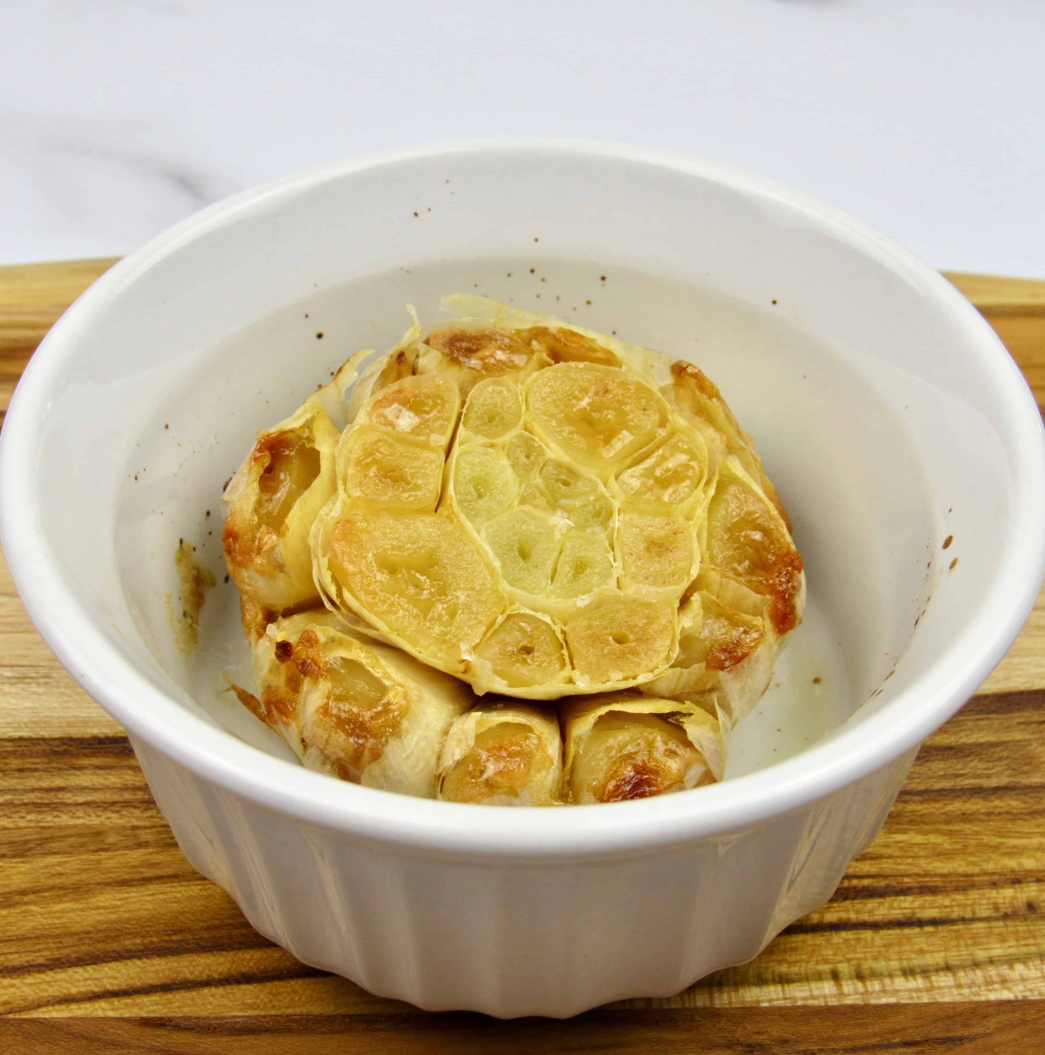 roasted head of garlic in white ramekin