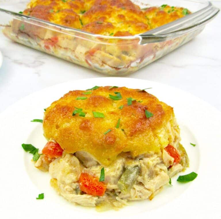 piece of chicken pot pie casserole on white plate with casserole in the background