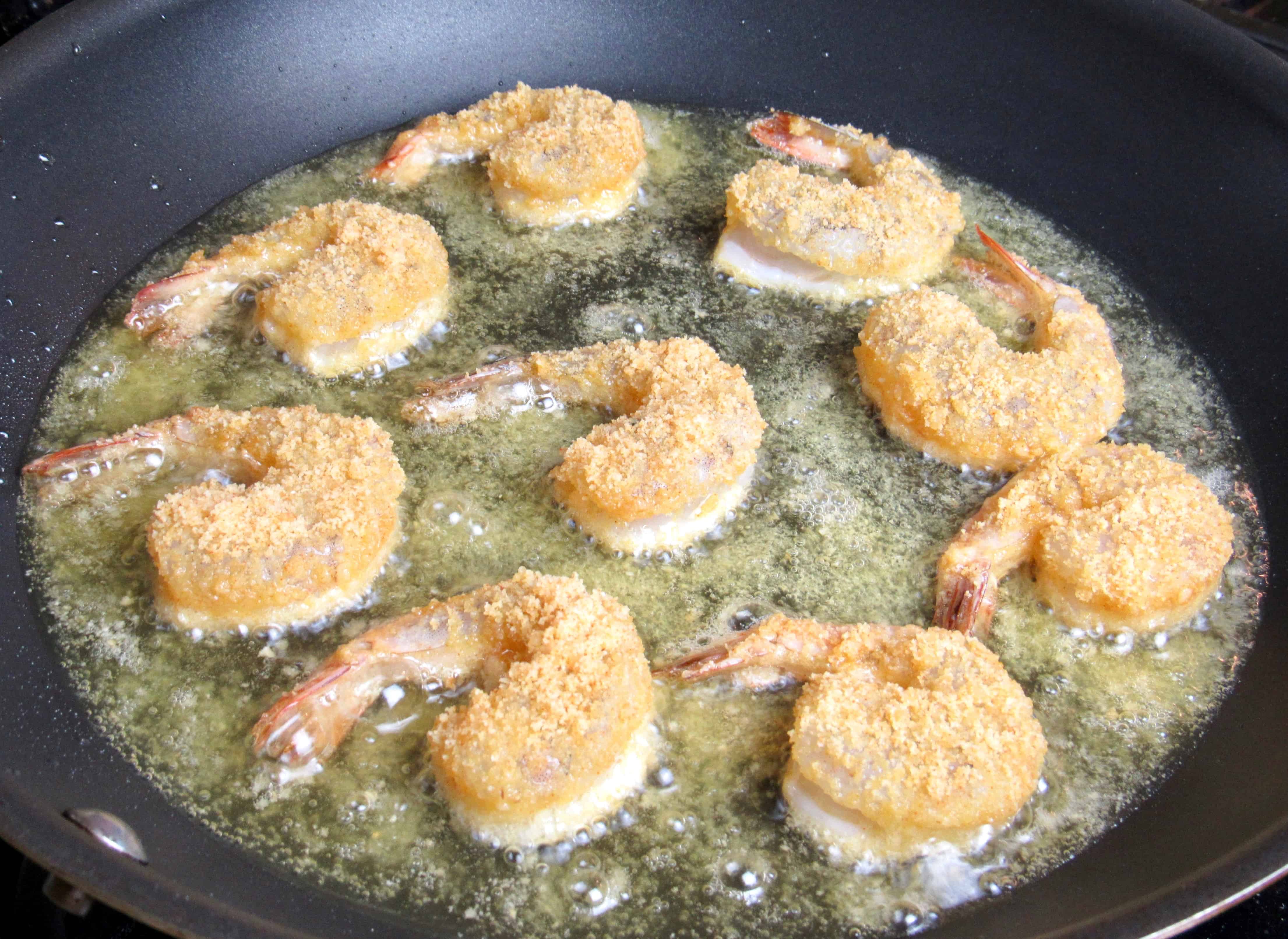 breaded shrimp frying in skillet with oil