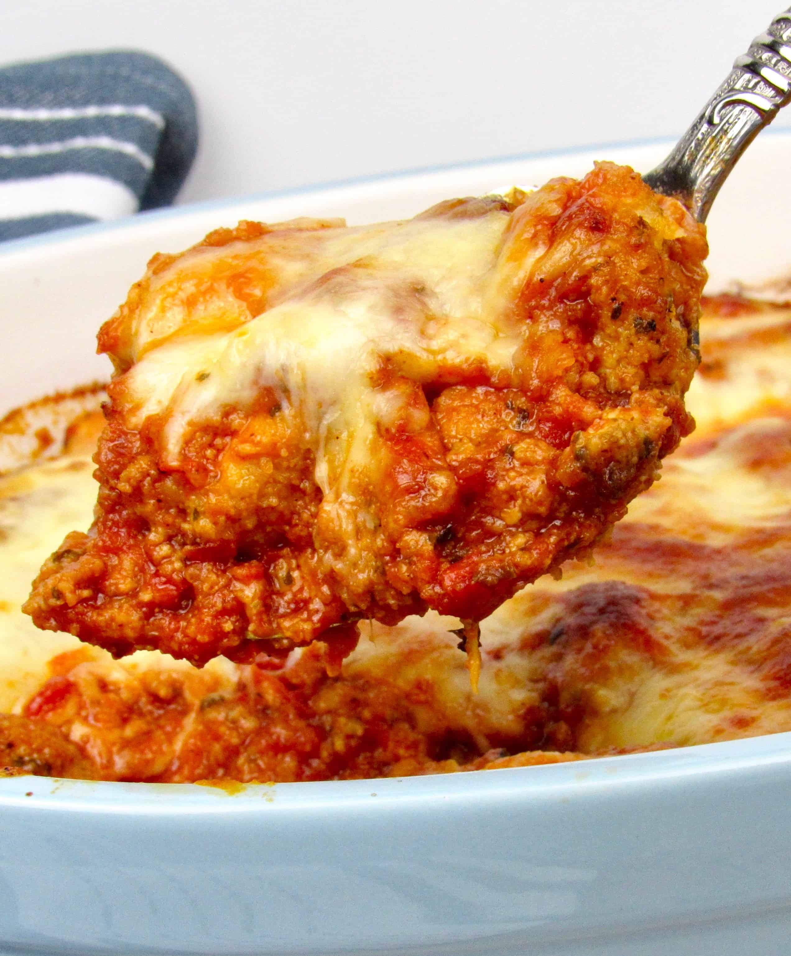 Chicken Parmesan Casserole being spooned out of baking dish