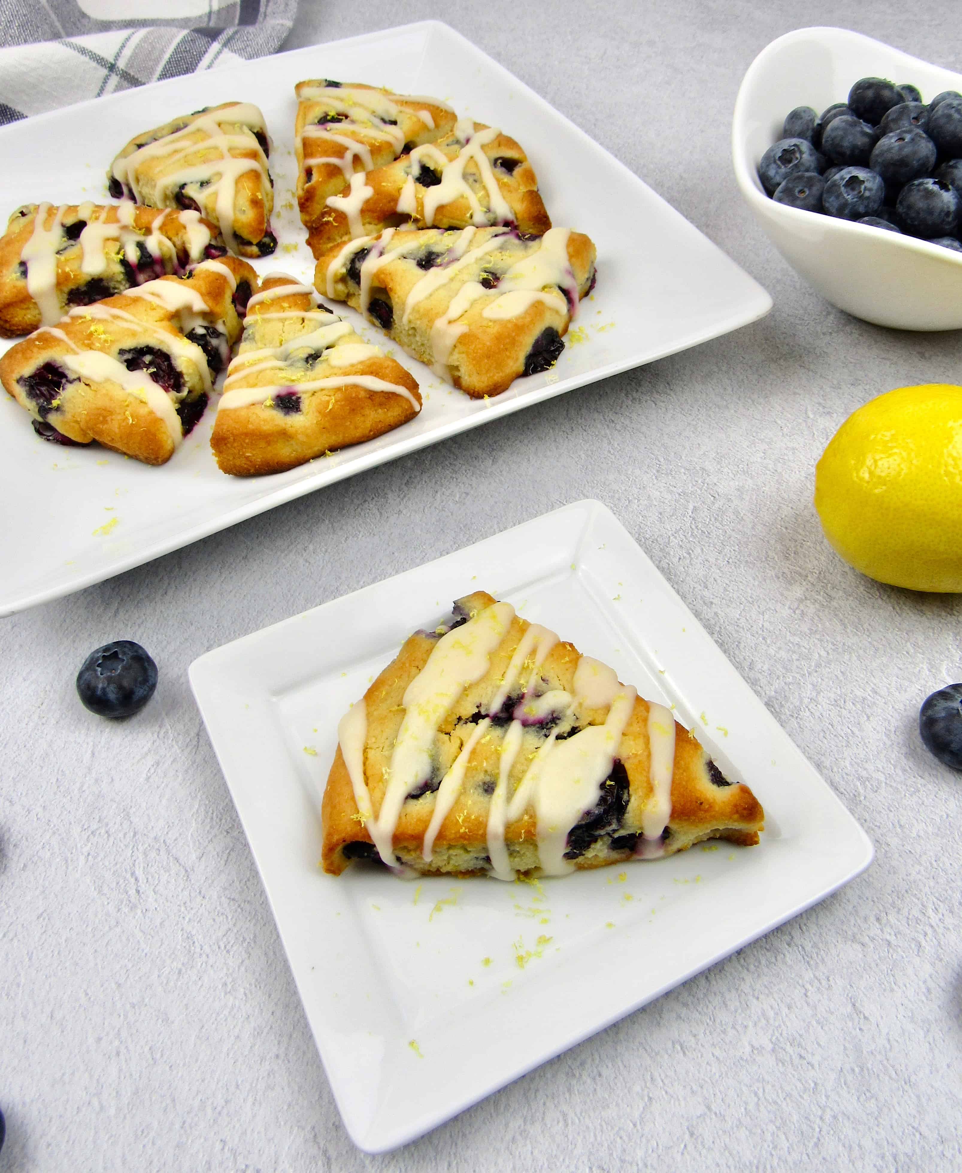 overhead view of blueberry lemon scones with 7 on one plate and 1 on another