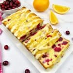 overhead view of cranberry orange bread cut into slices on white plate
