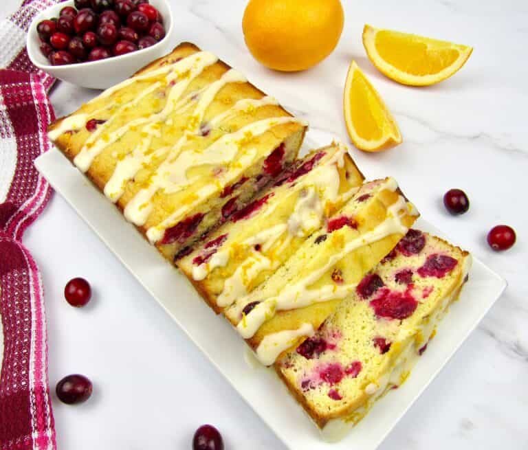 overhead view of cranberry orange bread cut into slices on white plate
