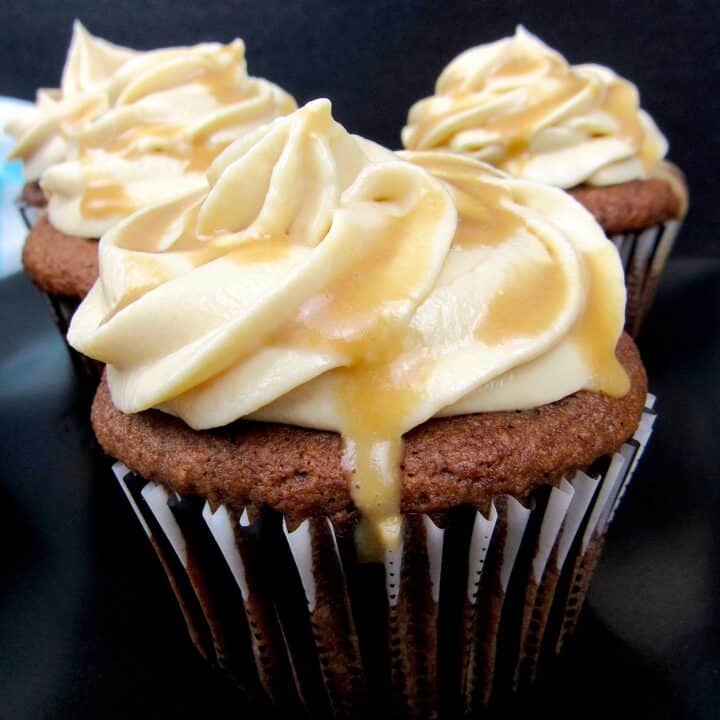 Salted Caramel Chocolate Cupcakes on black plate with caramel dripping off