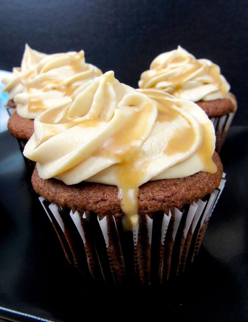 Salted Caramel Chocolate Cupcakes on black plate with caramel dripping off