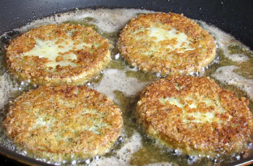 4 green tomatoes frying in skillet