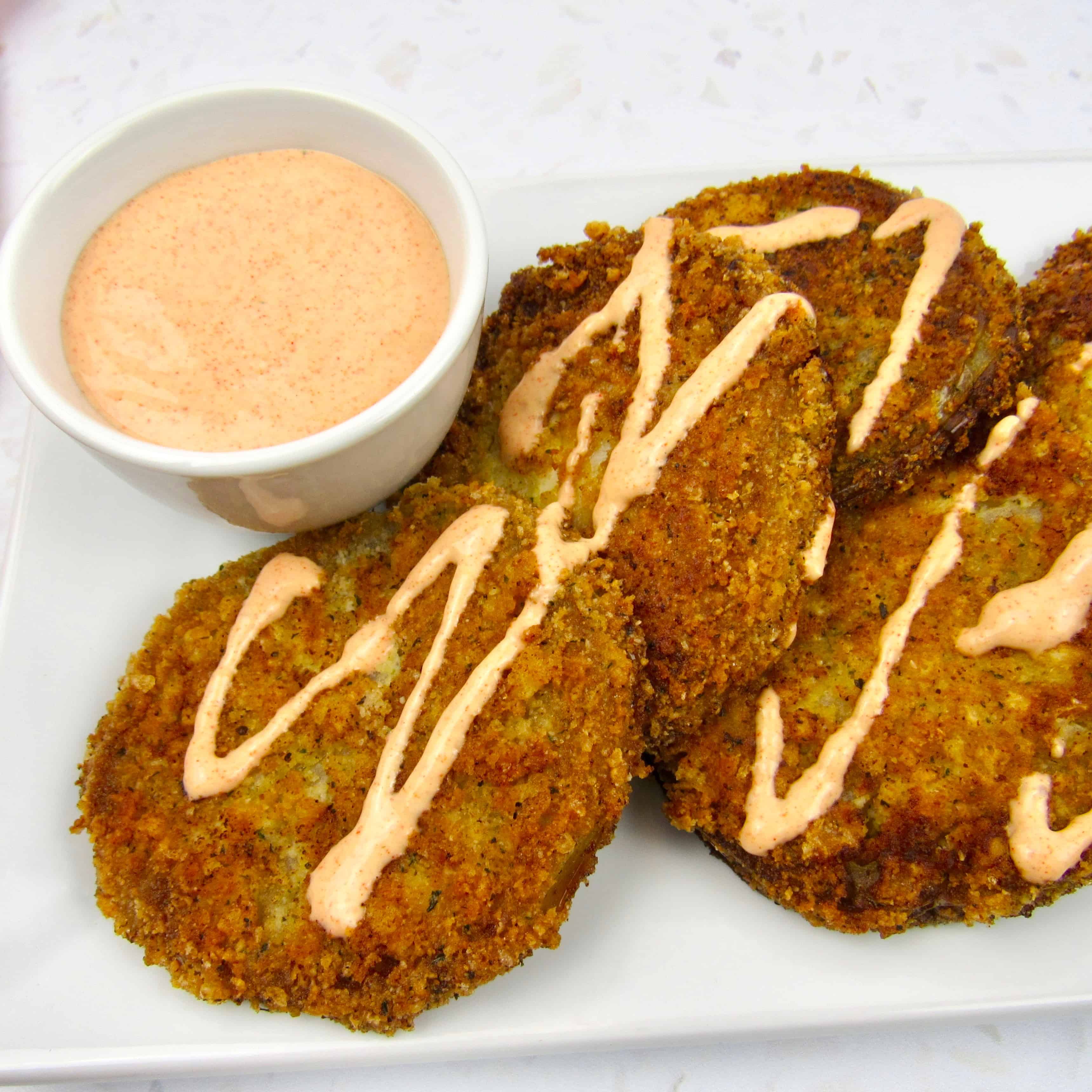 fried green tomatoes with side of dipping sauce on white plate