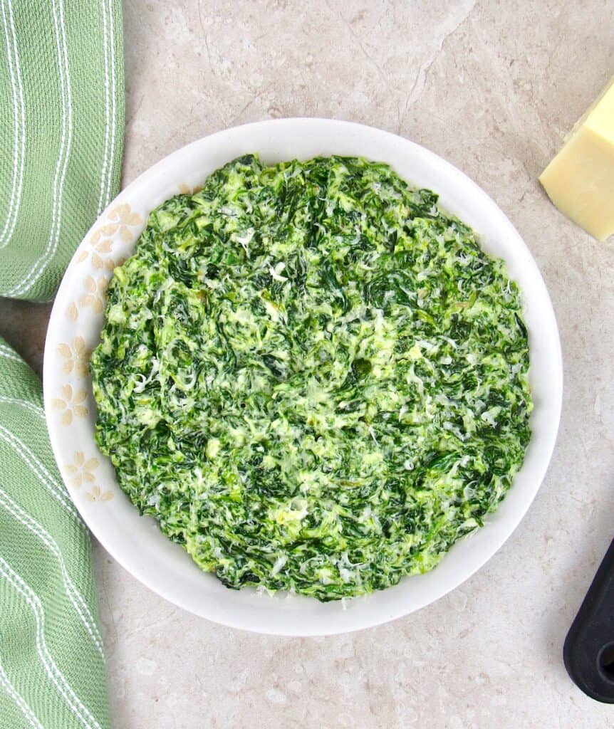 overhead view of a bowl of creamed spinach with grated cheese on top