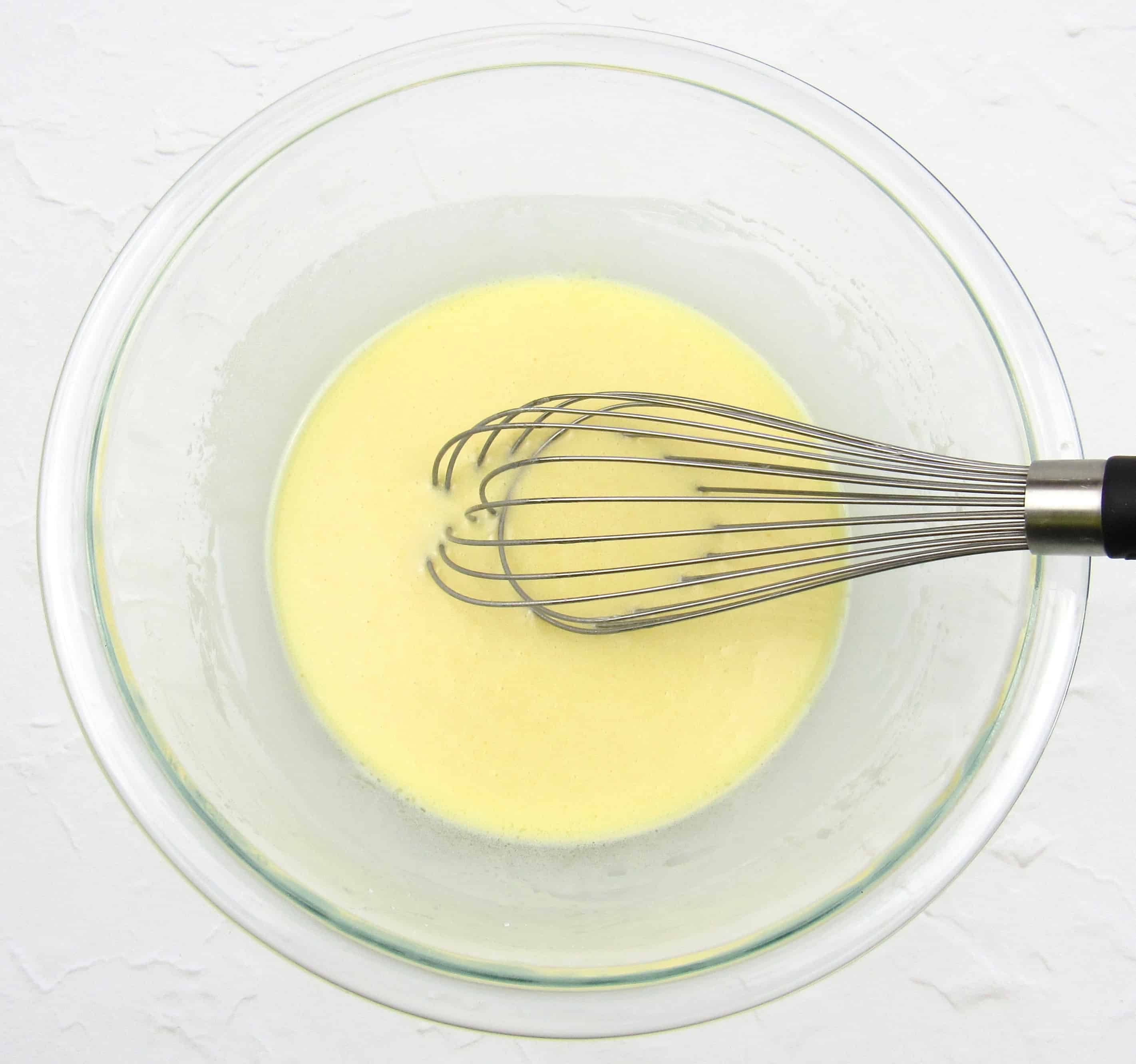 melted raw cacao butter in glass bowl with whisk