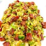 closeup of Brussels Sprouts with Hot Bacon Dressing in white bowl with bacon on top