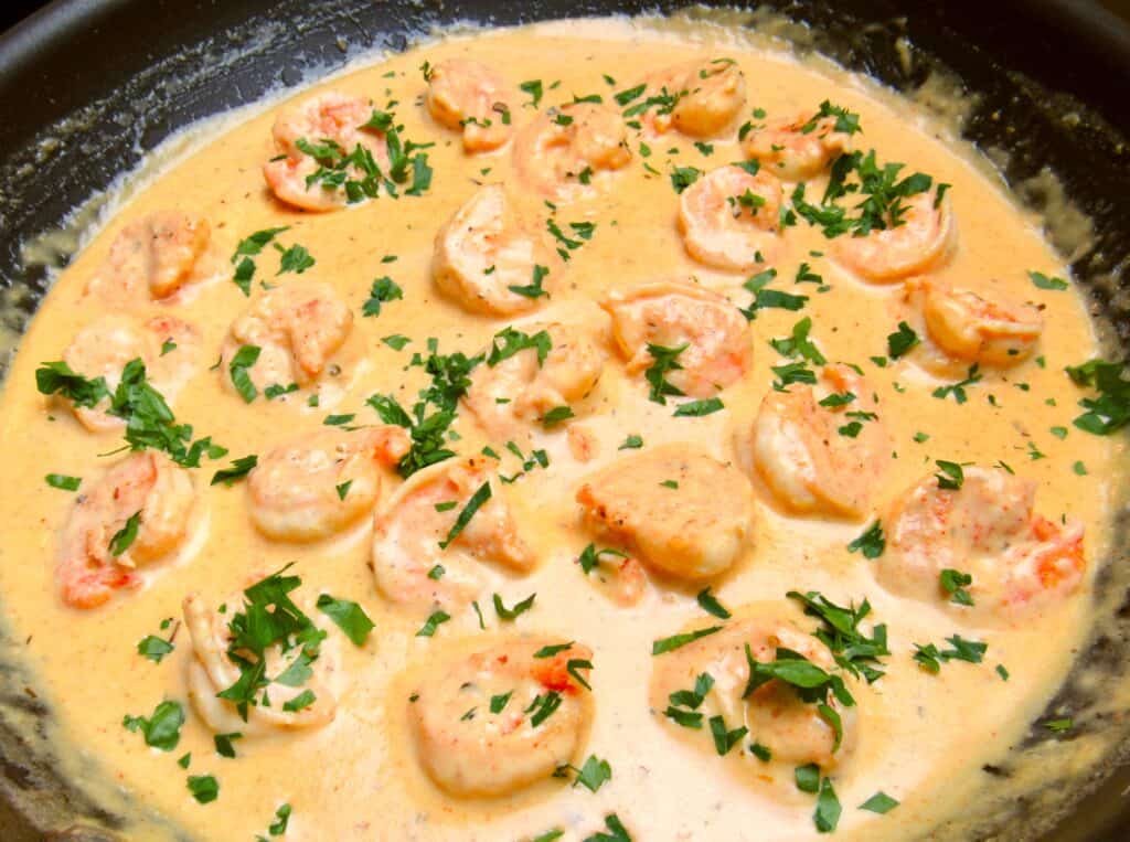 cajun shrimp cooking in skillet with parsley on top