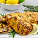 closeup of citrus glazed grilled chicken with bowl of fruit in background