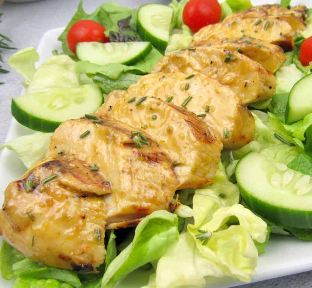 sliced grilled chicken over a salad