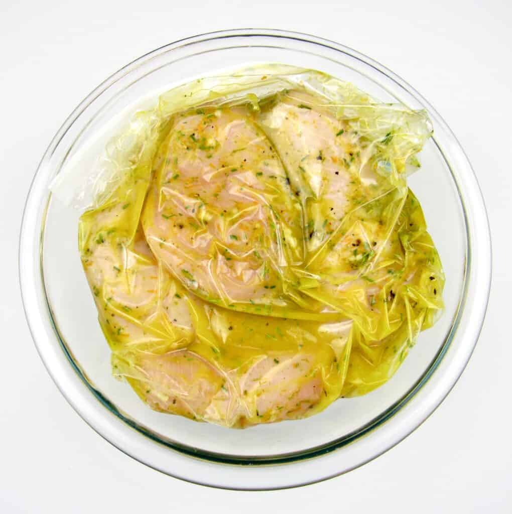 chicken breast marinating in baggies sitting in glass bowl