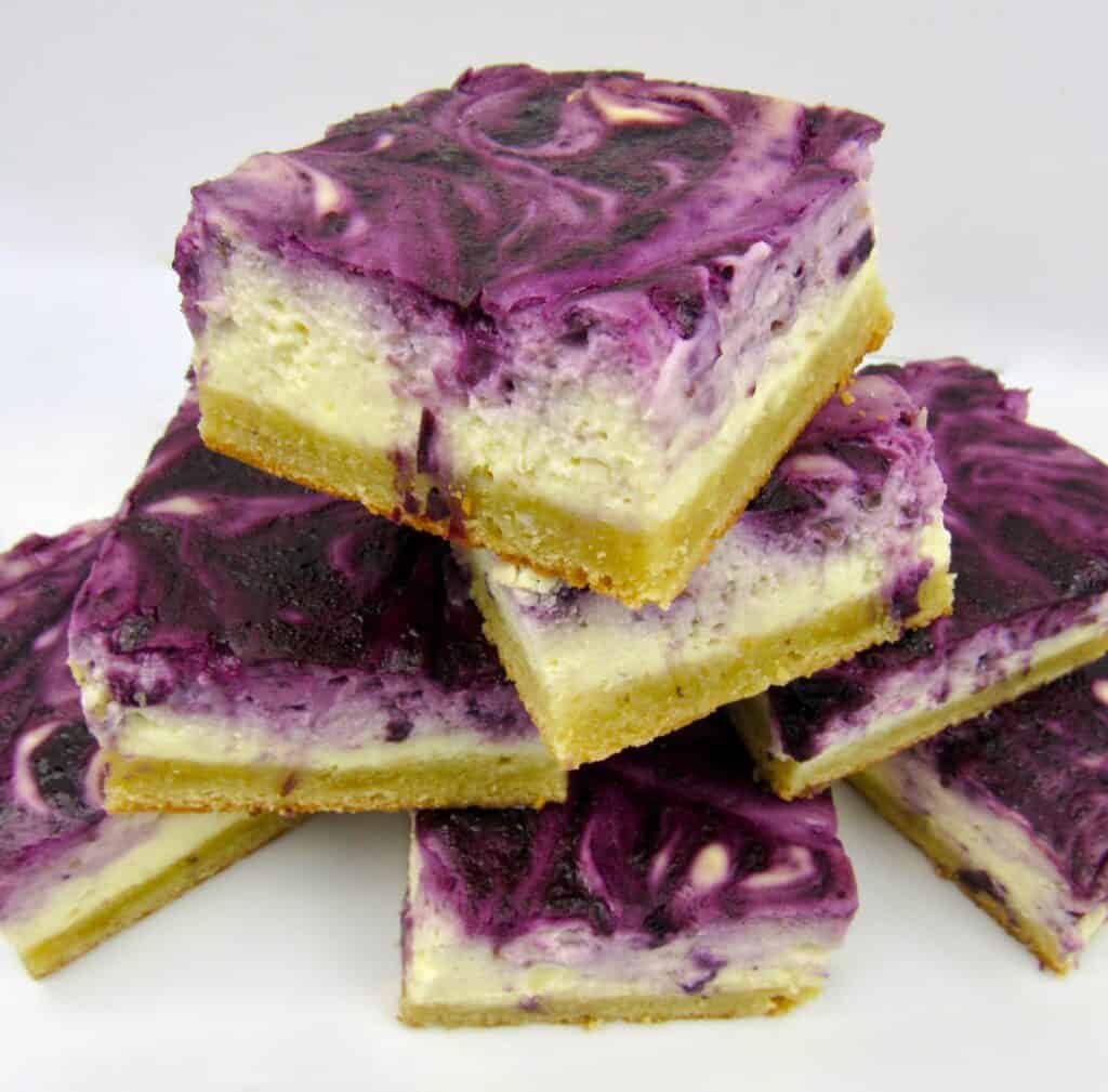 blueberry cheesecake bars stacked on white plate