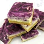 blueberry cheesecake bars stacked up on white plate