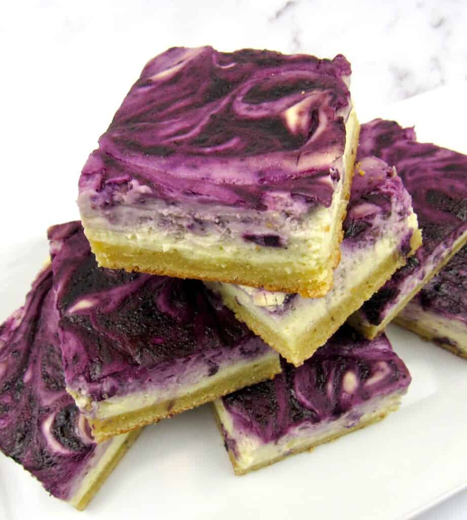 blueberry cheesecake bars stacked up on white plate