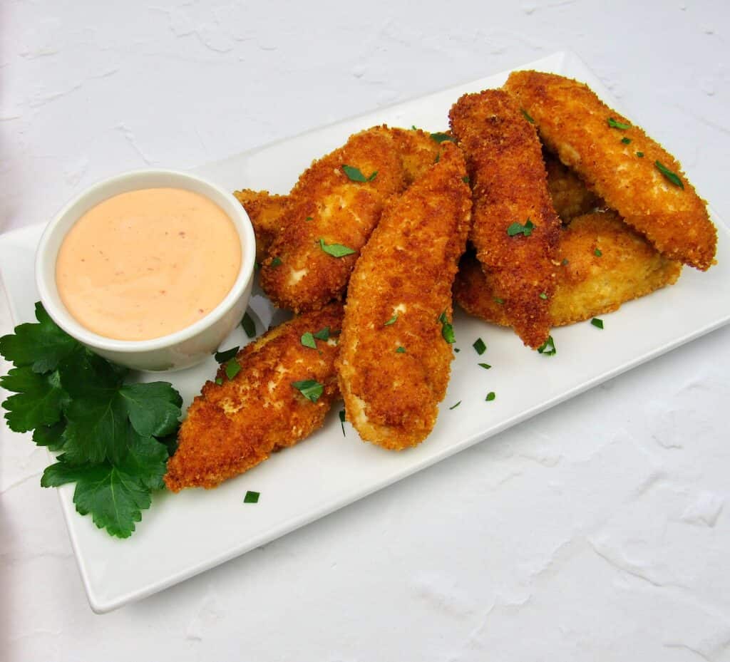 chicken tenders on white plate with parsley garnish