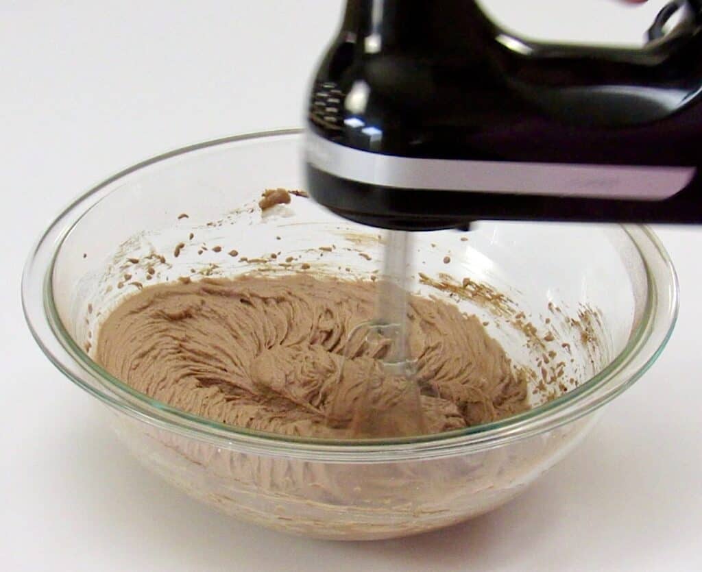 chocolate mousse ingredients in glass bowl being mixed with hand mixer