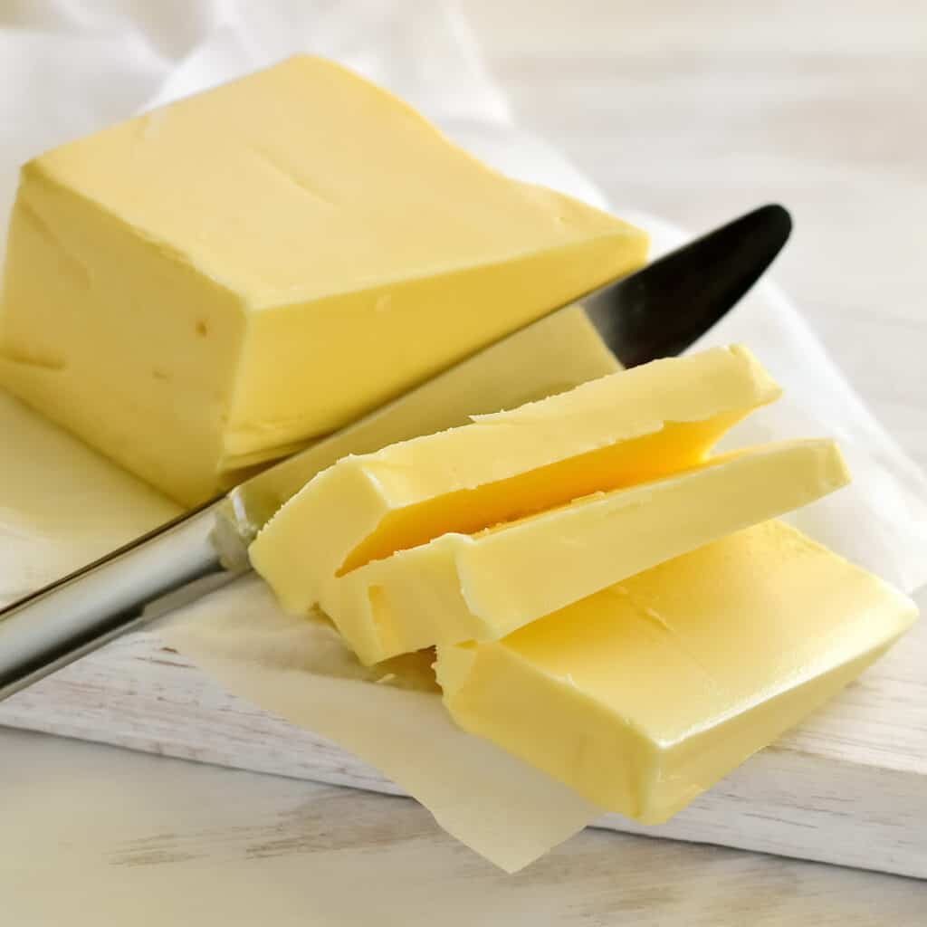 Butter with butter knife and 3 slices cut