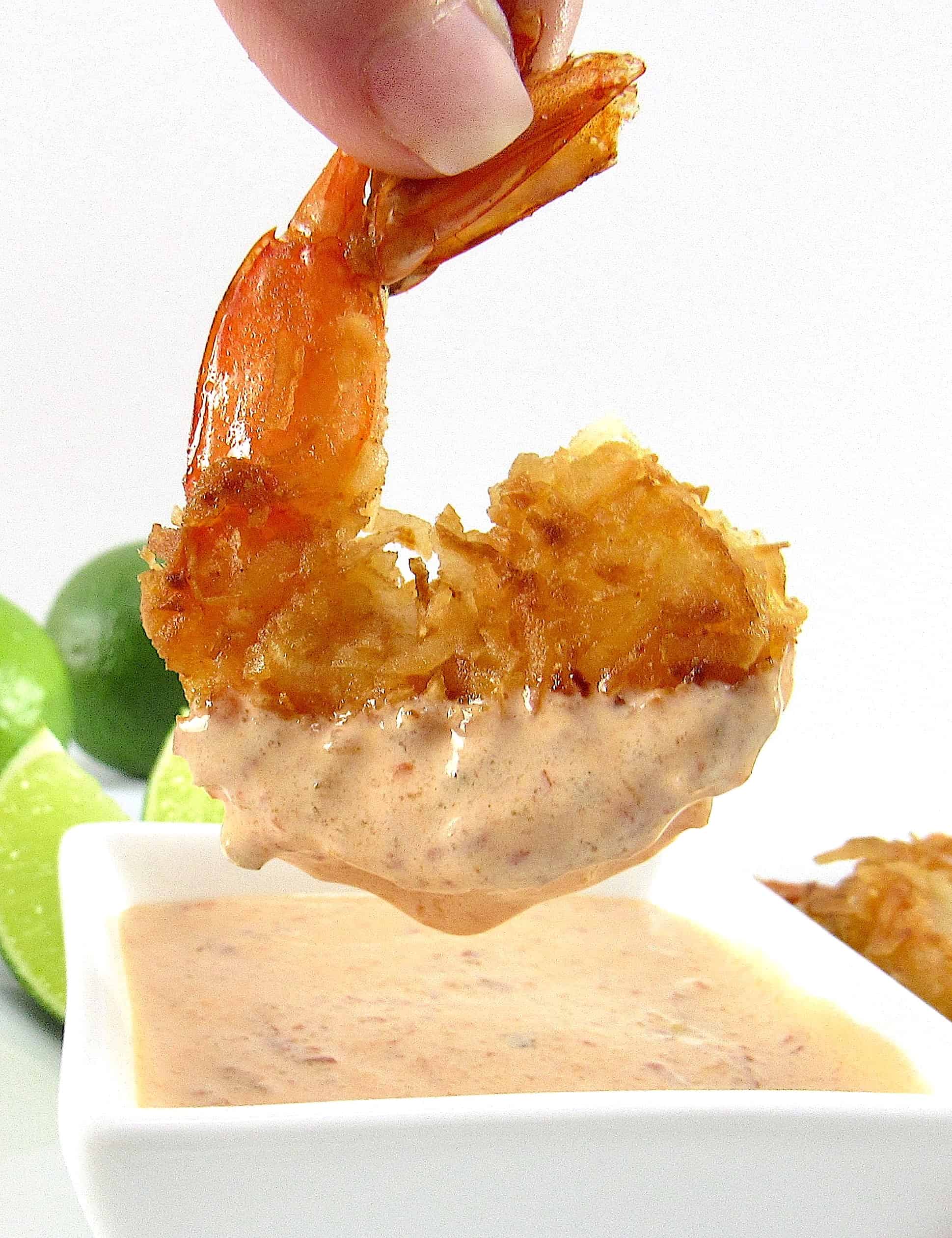 coconut shrimp being dipping into sauce