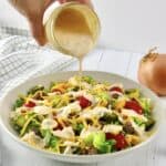 cheeseburger salad with dressing being poured over the top