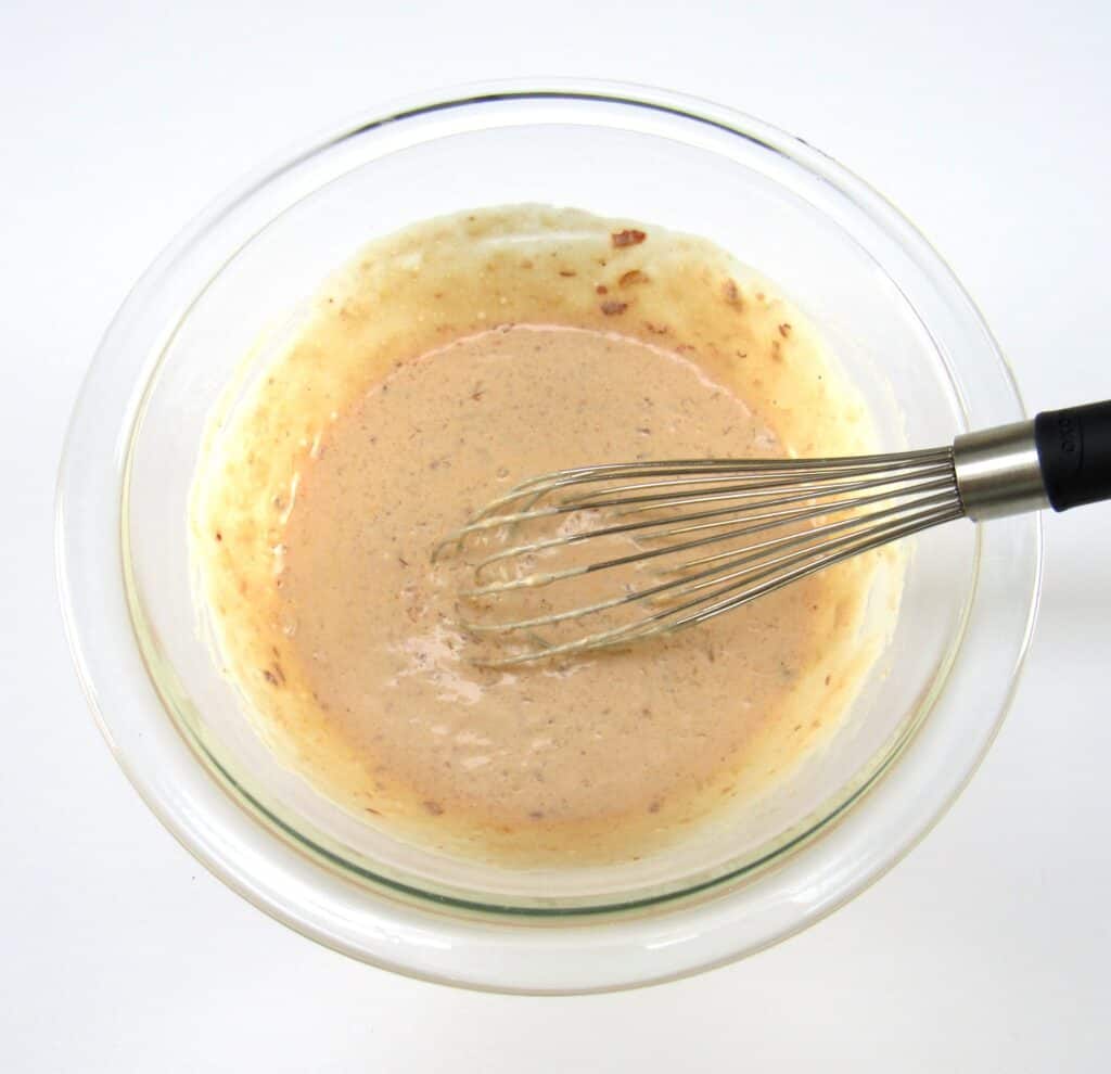 coconut shrimp dipping sauce in glass bowl mixed with whisk