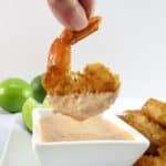 coconut shrimp being dipped into sauce