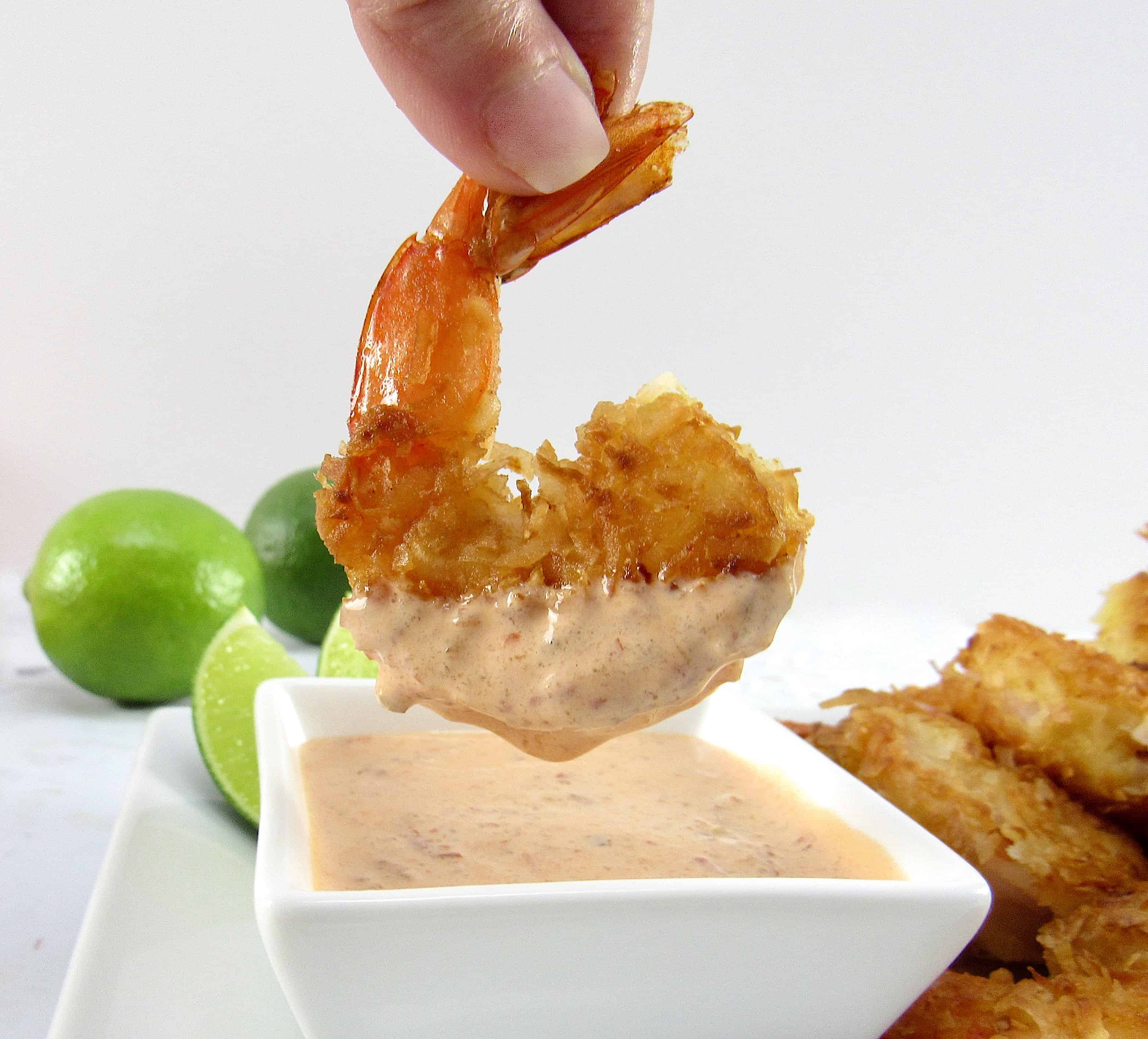 coconut shrimp being dipped into sauce