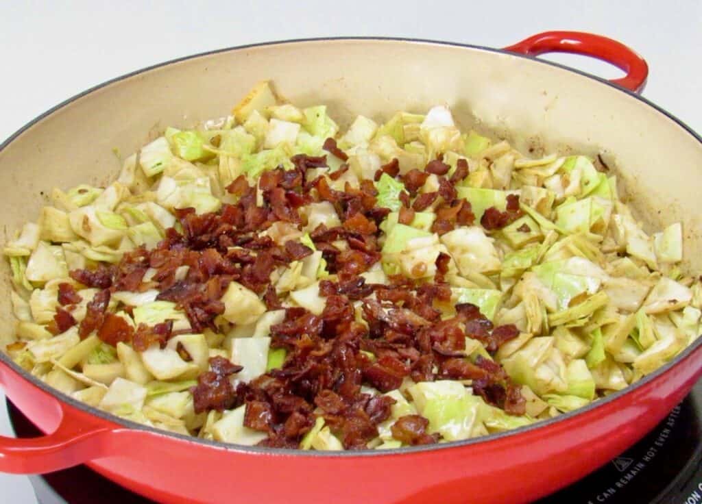 fried cabbage in skillet topped with crumbled bacon