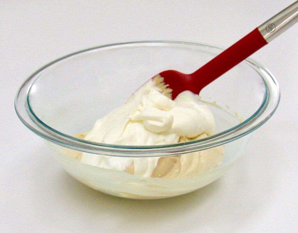 peanut butter mousse with whip cream on top in glass bowl