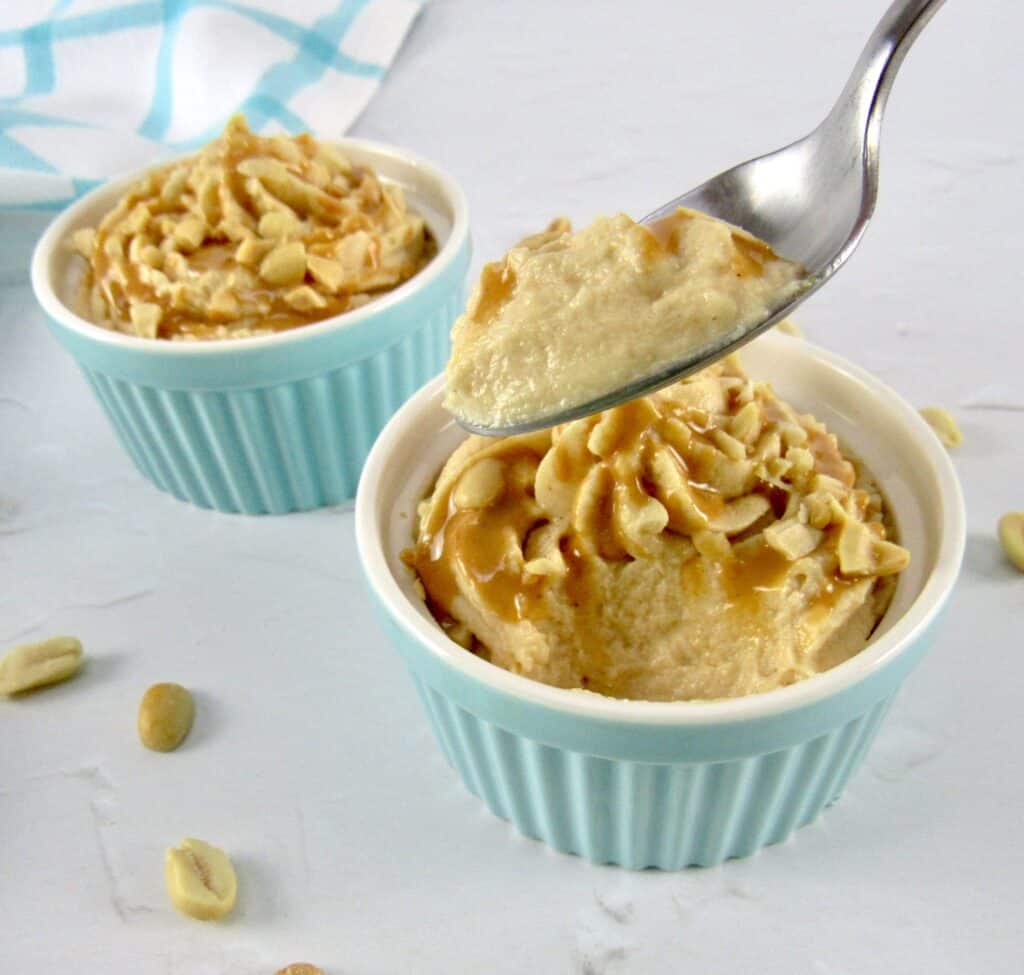 closeup of peanut butter mousse in turquoise ramekin with bite held up with spoon