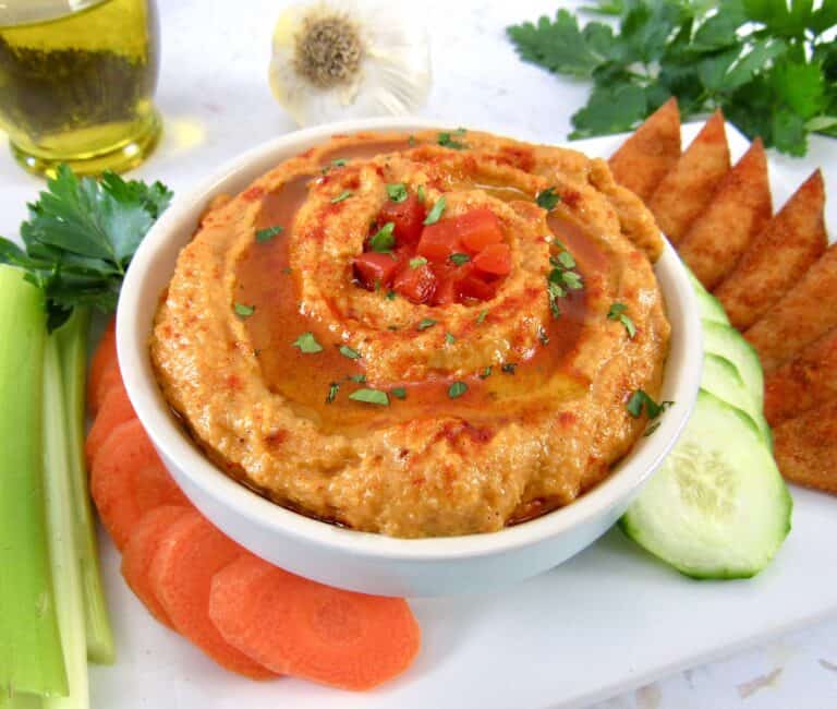 roasted pepper cauliflower hummus in white bowl on platter with veggies