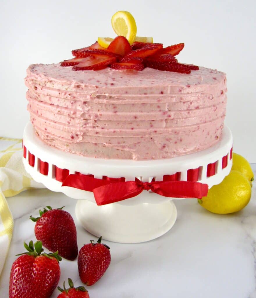 strawberry cake on cake stand with strawberries on top